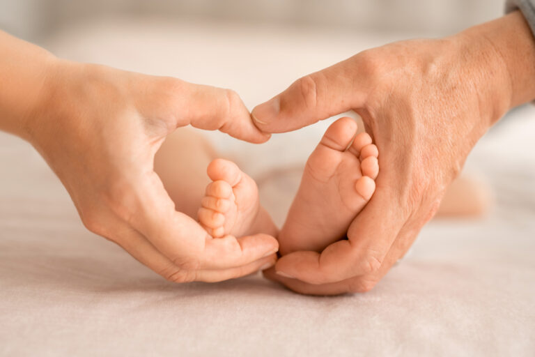 A little baby feet in mother ans father palms in a heart shape